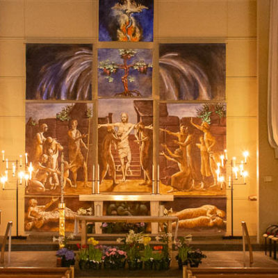 The sanctuary decorated for Easter, including candles, flowers, and large banners