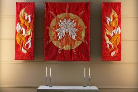 The three-part Pentecost quilt, in red with orange, yellow, and white flames.