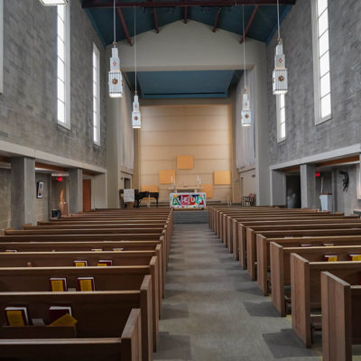 The sanctuary at University Lutheran Church includes a long line of wooden pews on each side of the center aisle, facing an altar decorated with an "Alleluia" banner.