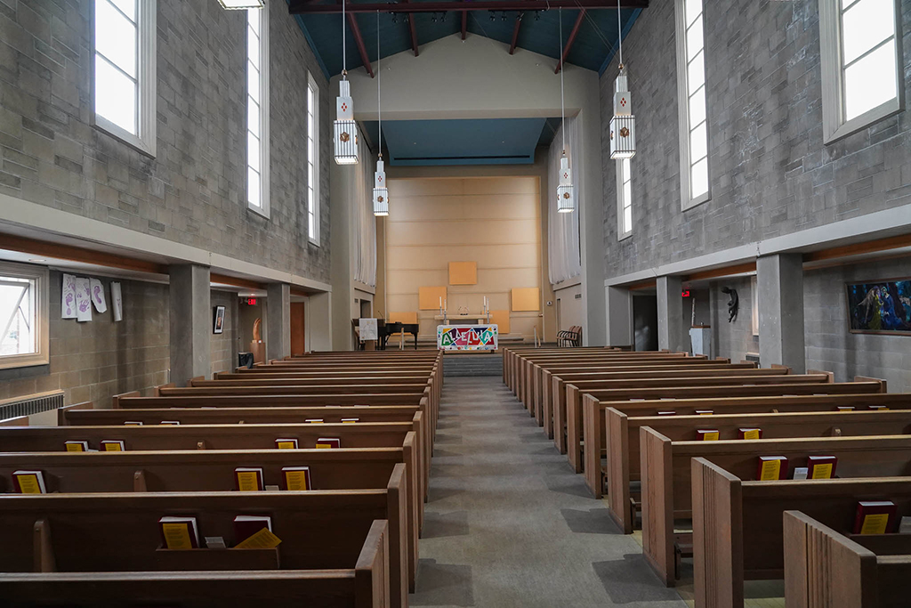 The sanctuary at University Lutheran Church includes a long line of wooden pews on each side of the center aisle, facing an altar decorated with an "Alleluia" banner.