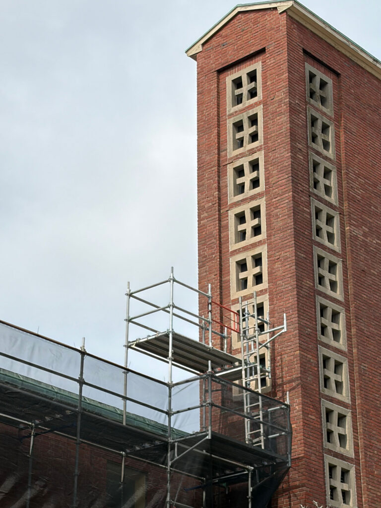 The University Lutheran bell tower with scaffolding creating a platform near one of the lower cross-shaped windows.